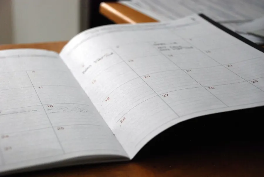 An open paper planner with a monthly calendar grid lying on a desk