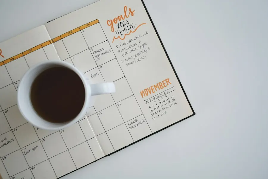 A cup of black coffee resting on an open monthly planner with handwritten goals for the month
