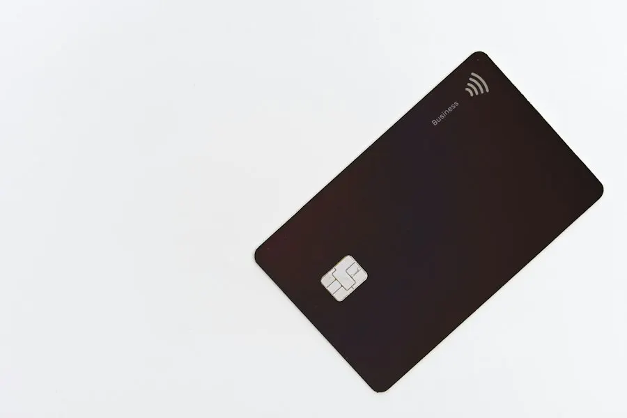 A plain dark payment card with a chip lying on a white surface
