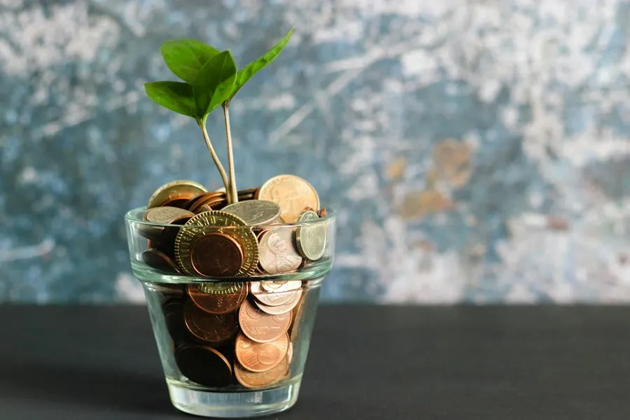 A small glass jar filled with coins, with a green seedling growing out of the top